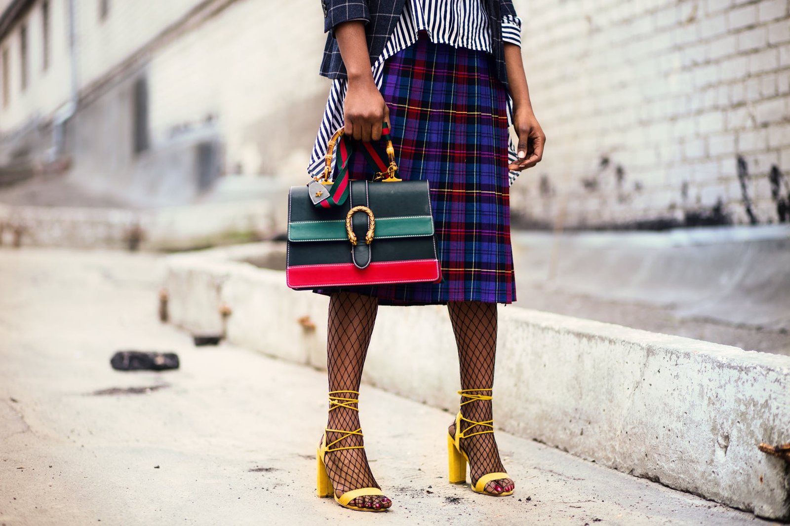 woman holding green and red leather handbag