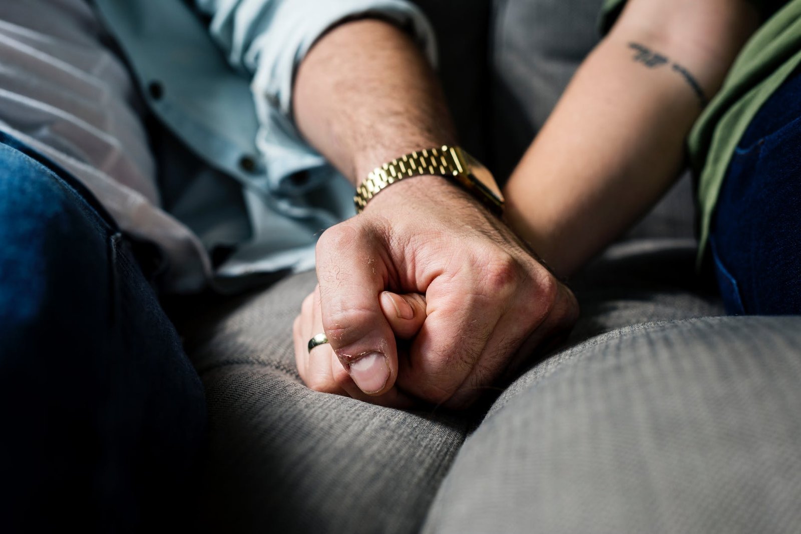 two person holding hands while sitting on grey cushion