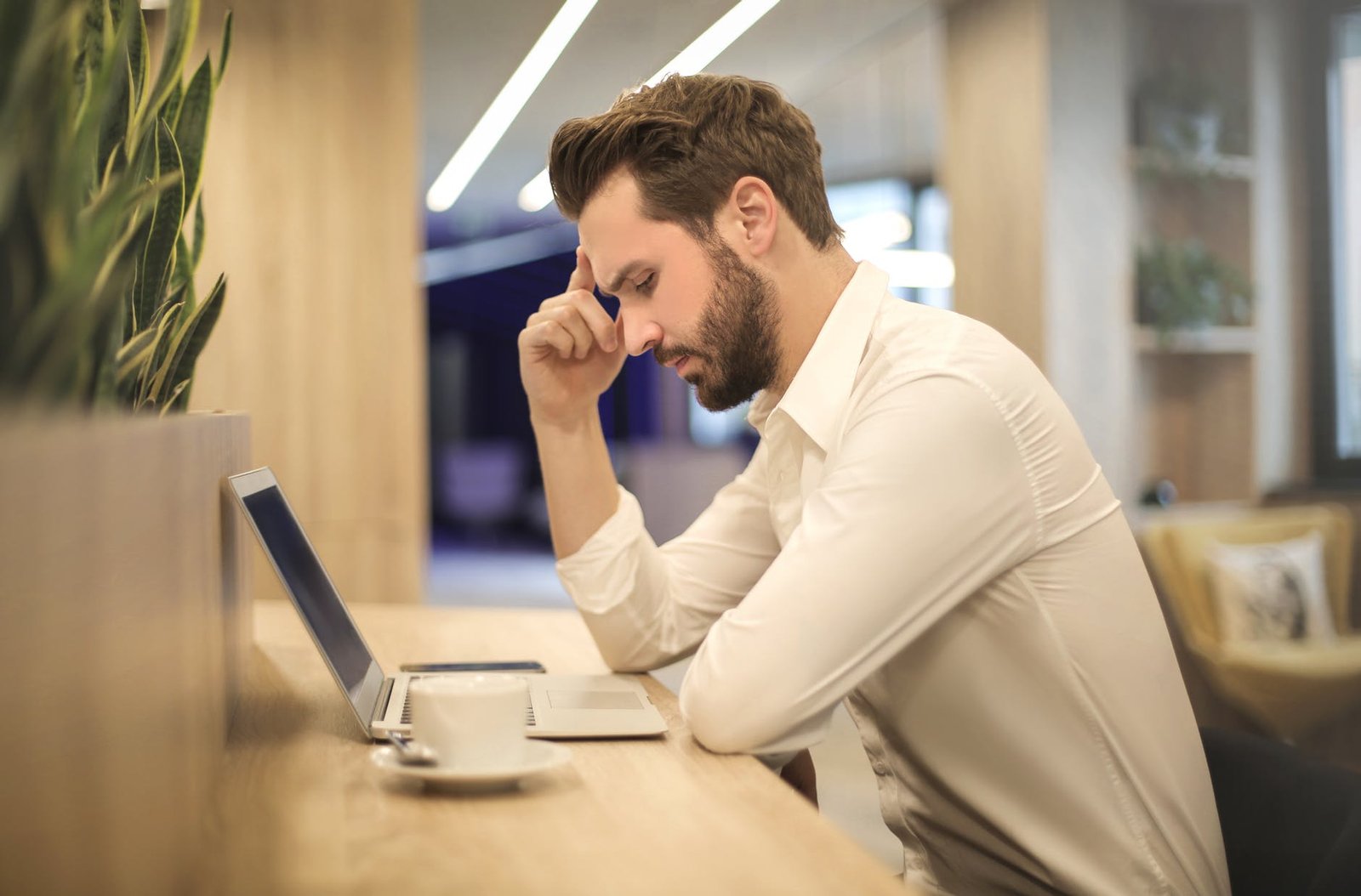 man with hand on temple looking at laptop