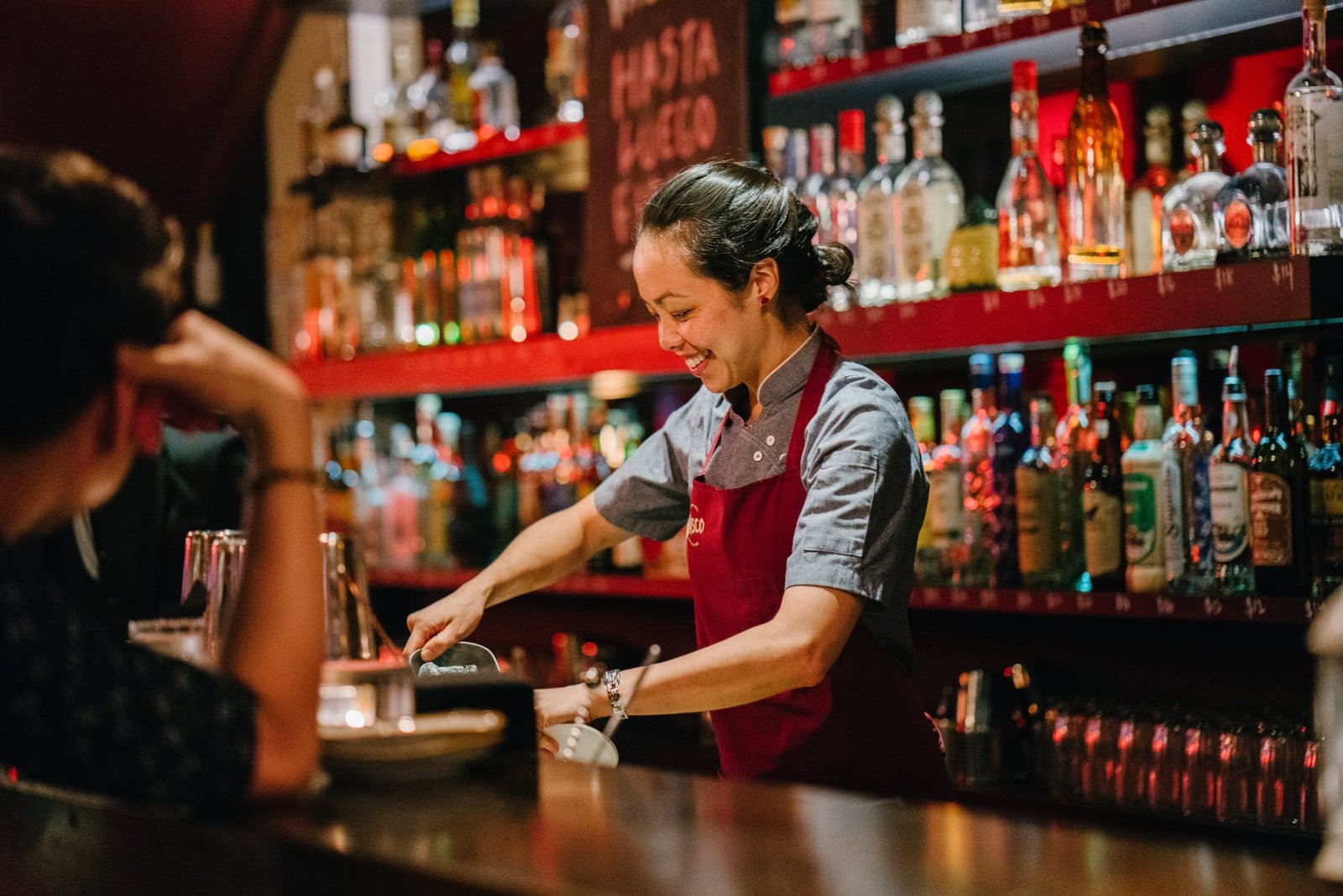 woman bartender smiling while mixing liqueurs